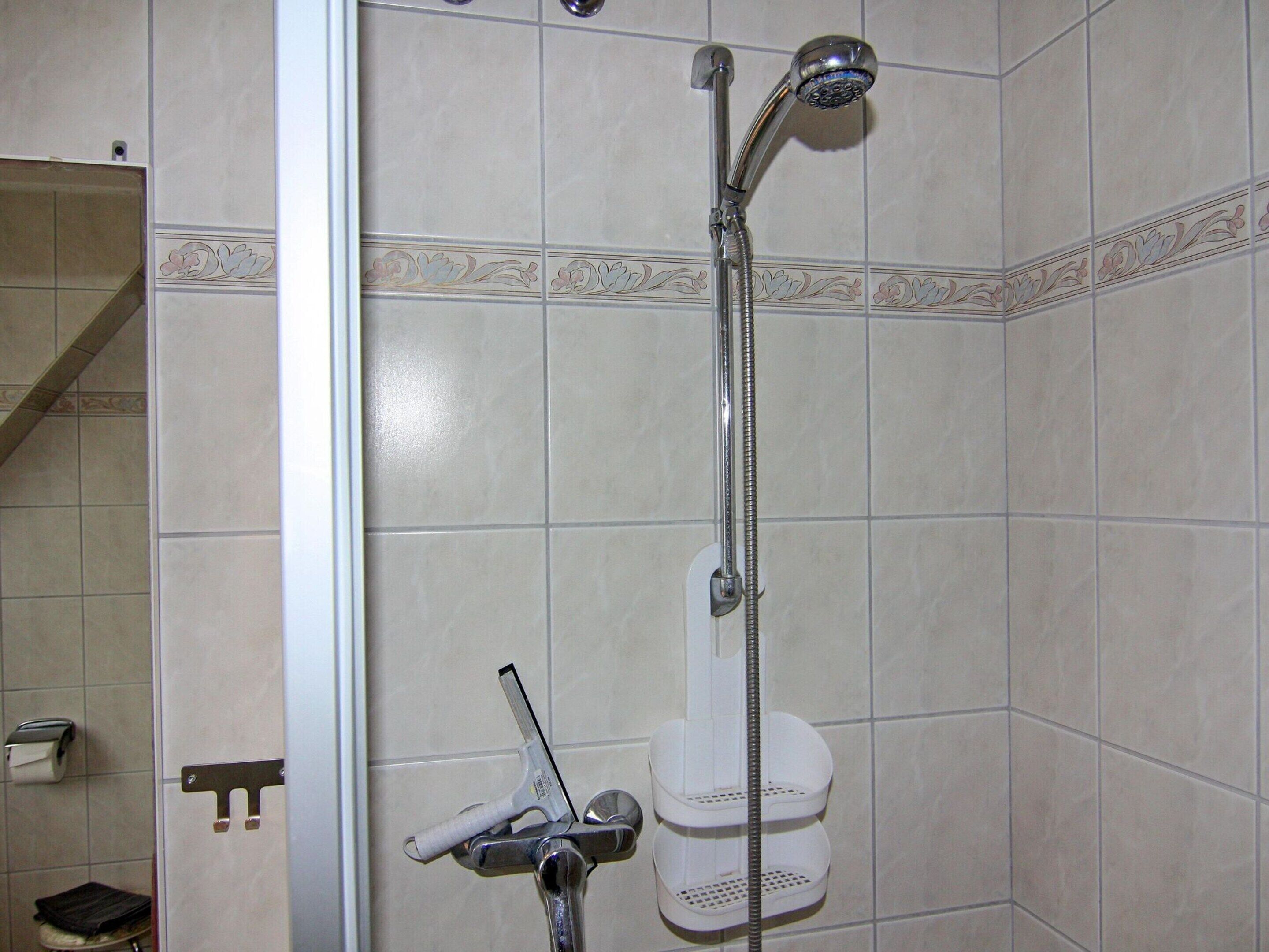 Une salle de bain avec une douche, des toilettes et un porte-serviettes.