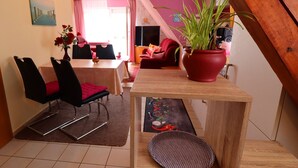 Un comedor con una mesa y sillas, una planta en maceta y vistas al salón.