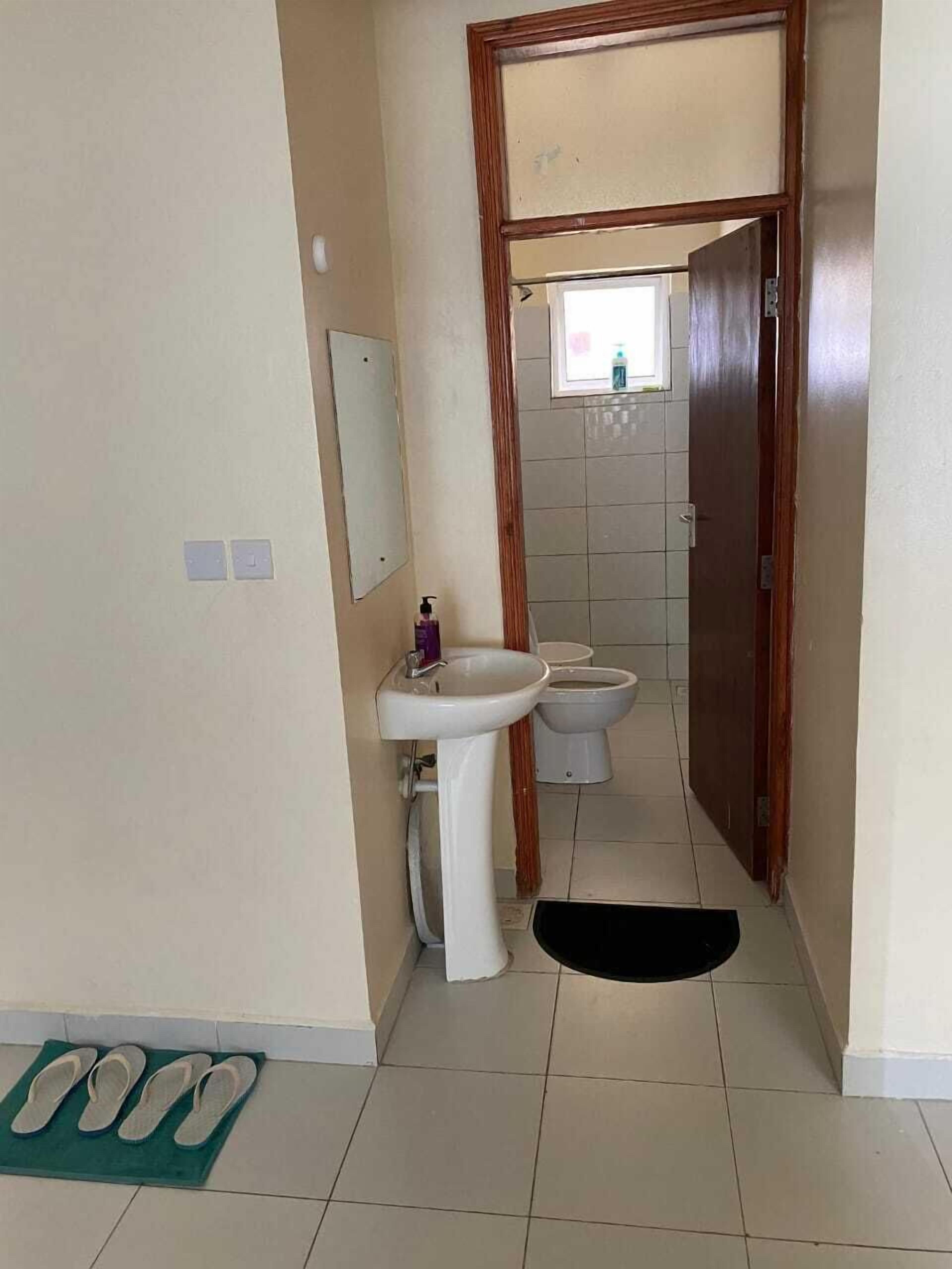 Een kleine badkamer met een wastafel, toilet en spiegel.