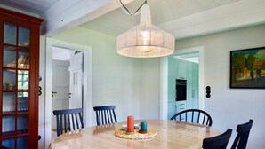 Un coin repas avec une table ronde en bois, des chaises noires et un luminaire suspendu.