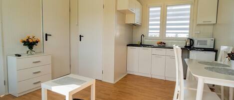 A compact, well-lit room with a kitchenette, a dining area, and a small seating space.