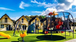 A playground with a trampoline, slides, and climbing structures, surrounded by houses. - Single-story Holiday Home, Pool, Jacuzzi (Ustronie Morskie)