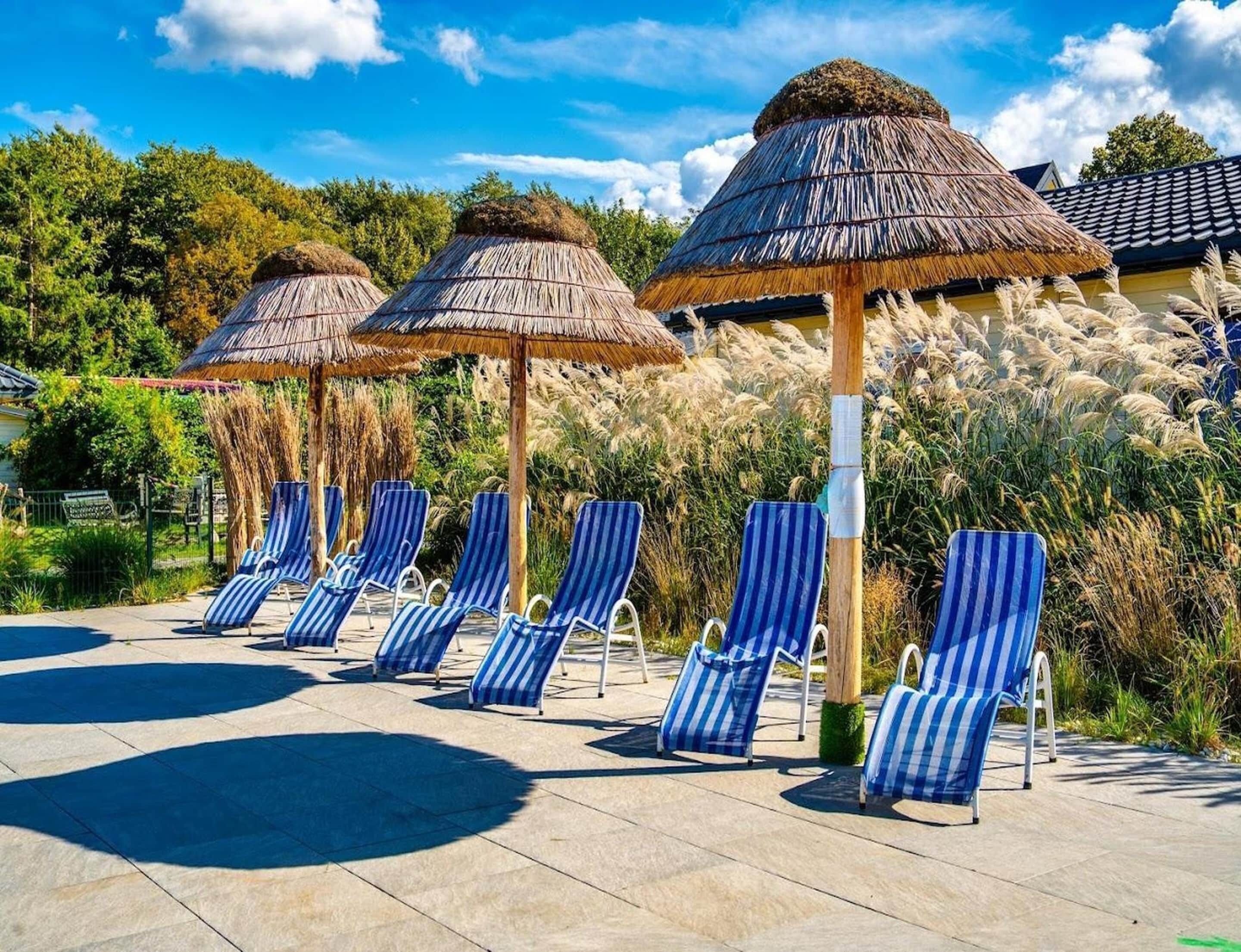 A poolside area with striped lounge chairs and thatched umbrellas.