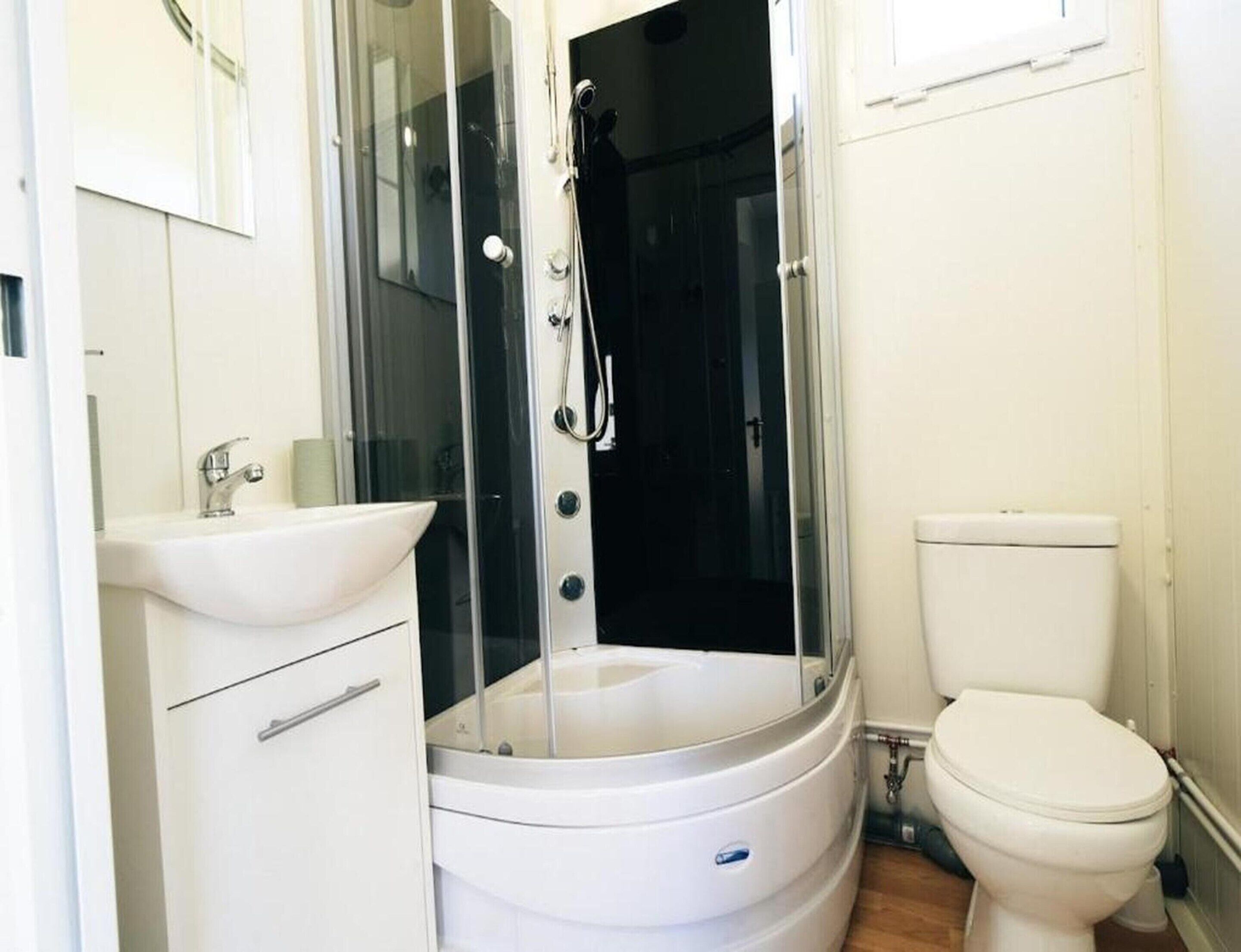 A modern bathroom with a glass-enclosed shower, a white sink, and a toilet.