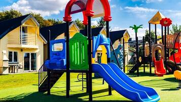 A playground with slides and climbing structures, surrounded by houses.