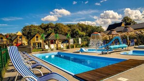 A pool area with lounge chairs, a water slide, and a small pool. - Single-story Holiday Home, Pool, Jacuzzi (Ustronie Morskie)