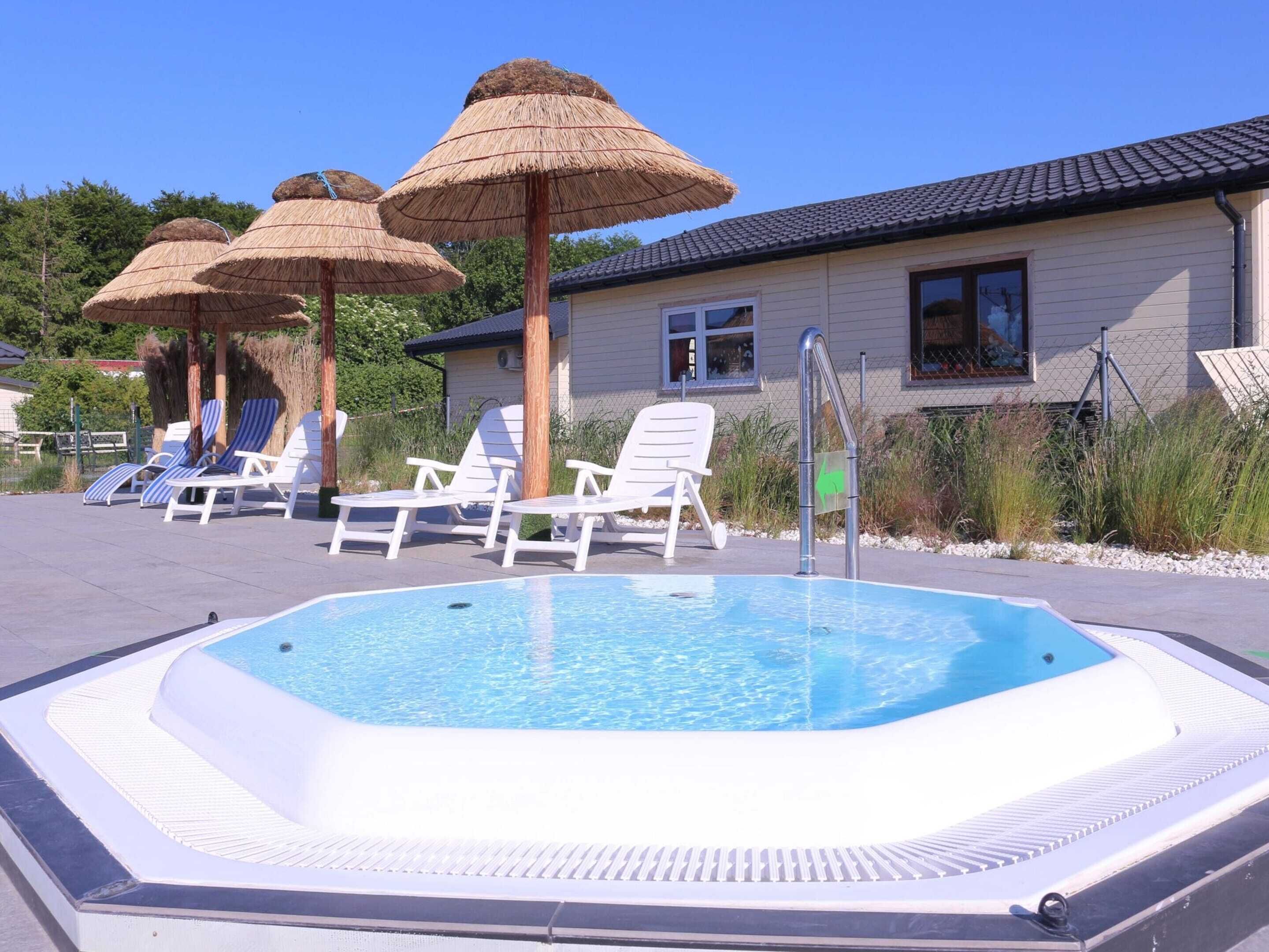 Una piscina con lettini e ombrelloni di paglia.