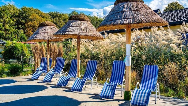 A poolside area with striped lounge chairs and thatched umbrellas. - Single-story Holiday Home, Pool, Jacuzzi (Ustronie Morskie)