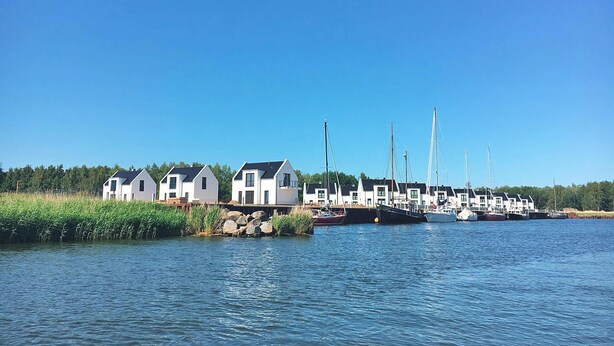 Una marina con varias casas blancas y barcos amarrados a la orilla del agua.