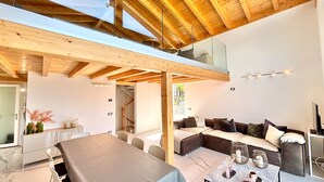 A modern interior with a high ceiling, a dining area, a sofa set, and a television. - Casa Monti Neues Modernes Haus in den Bergen von Monti di Vairano (Monti di Vairano)