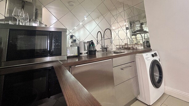A modern kitchen with a microwave, sink, and washing machine.
