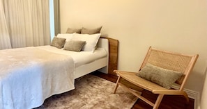 A bedroom with a bed, a chair, and a window with curtains.