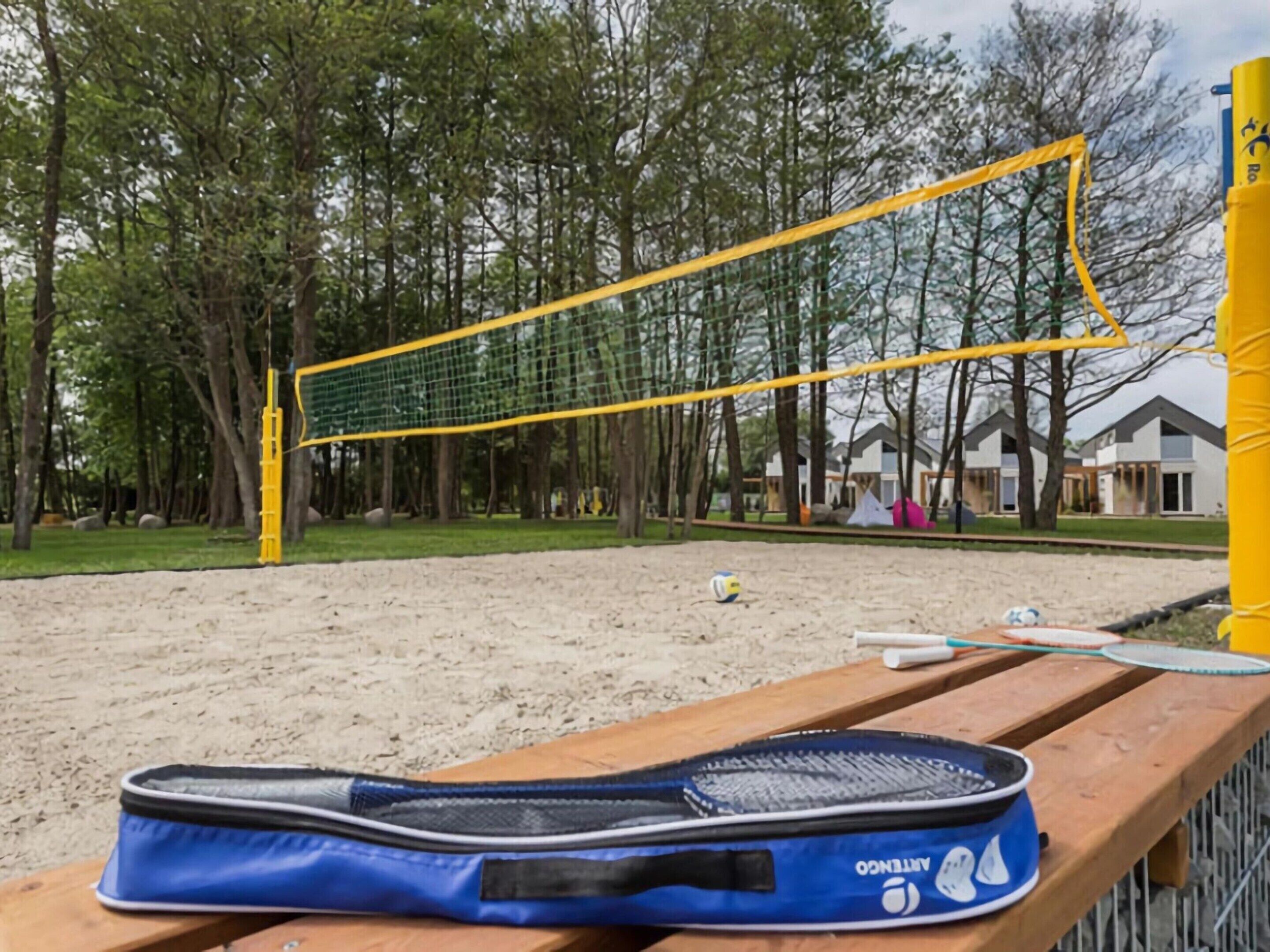 A beach volleyball net with a blue bag on a wooden bench.