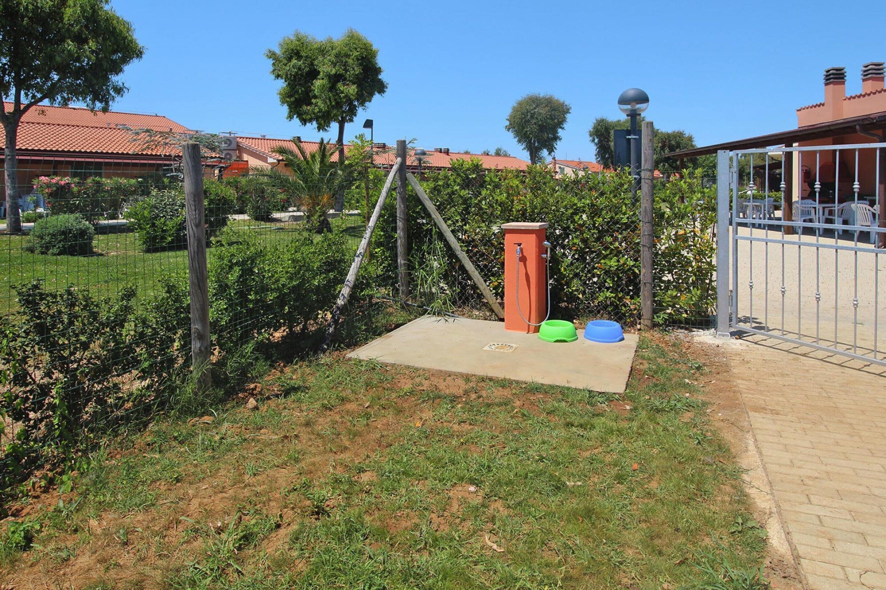 A fenced outdoor area with a concrete platform, a metal gate, and a red utility box.