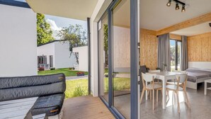 Un intérieur moderne avec une terrasse en bois, un coin repas et une vue sur l’extérieur.