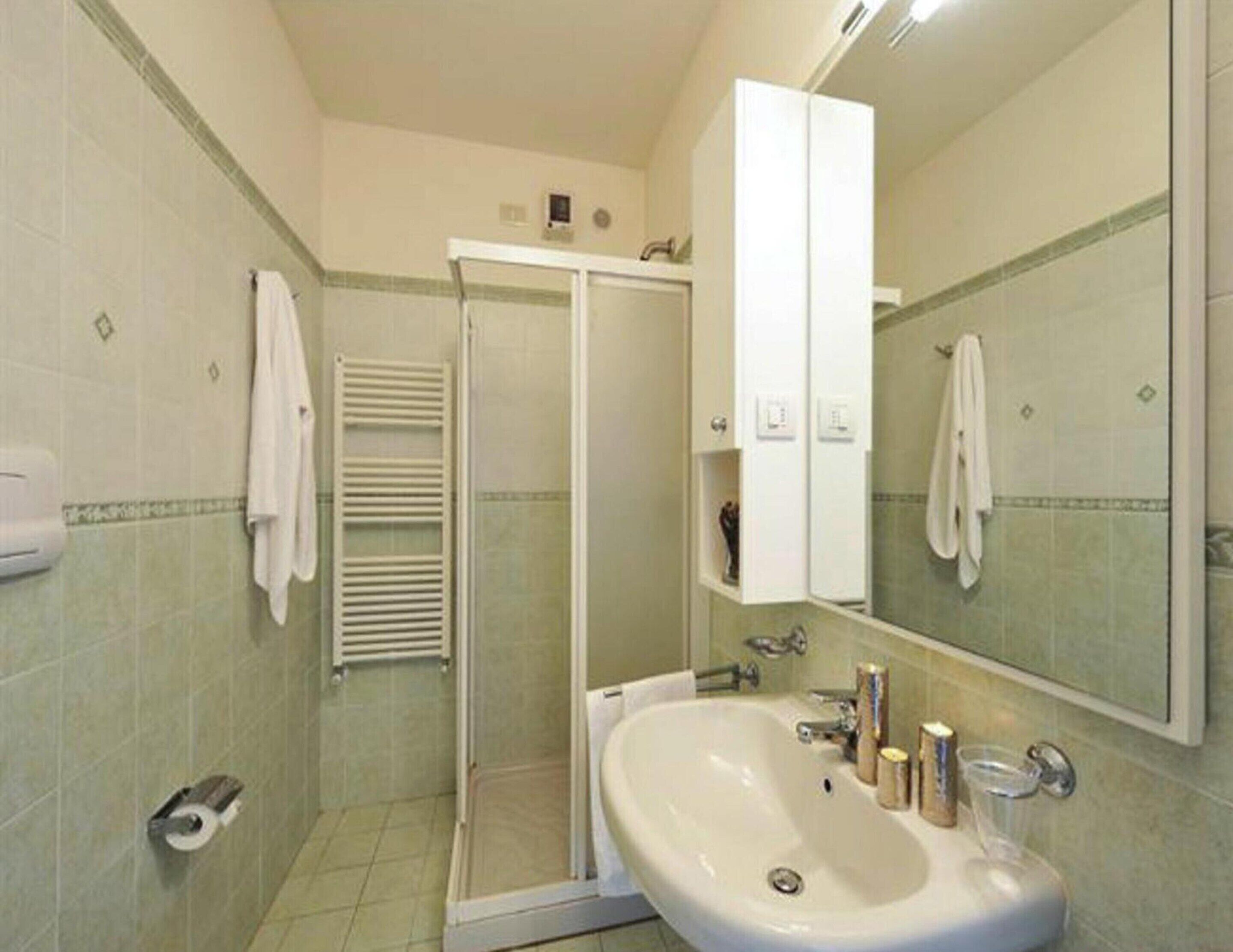 A bathroom with a shower, sink, and a mirror.