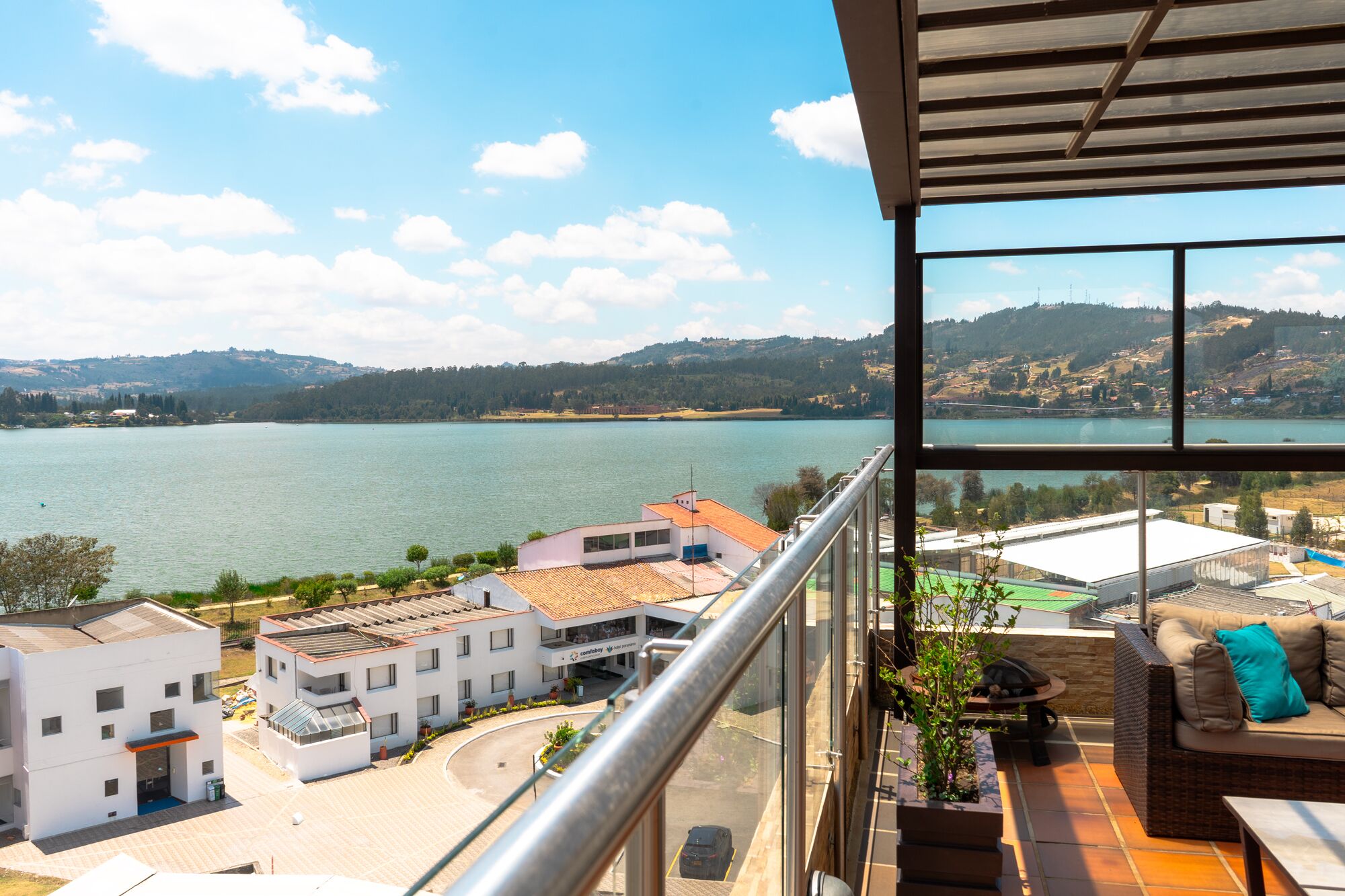 Ein Balkon mit Blick auf einen See, Gebäude und eine entfernte Hügelkette.
