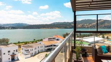 Ein Balkon mit Blick auf einen See, Gebäude und eine entfernte Hügelkette.