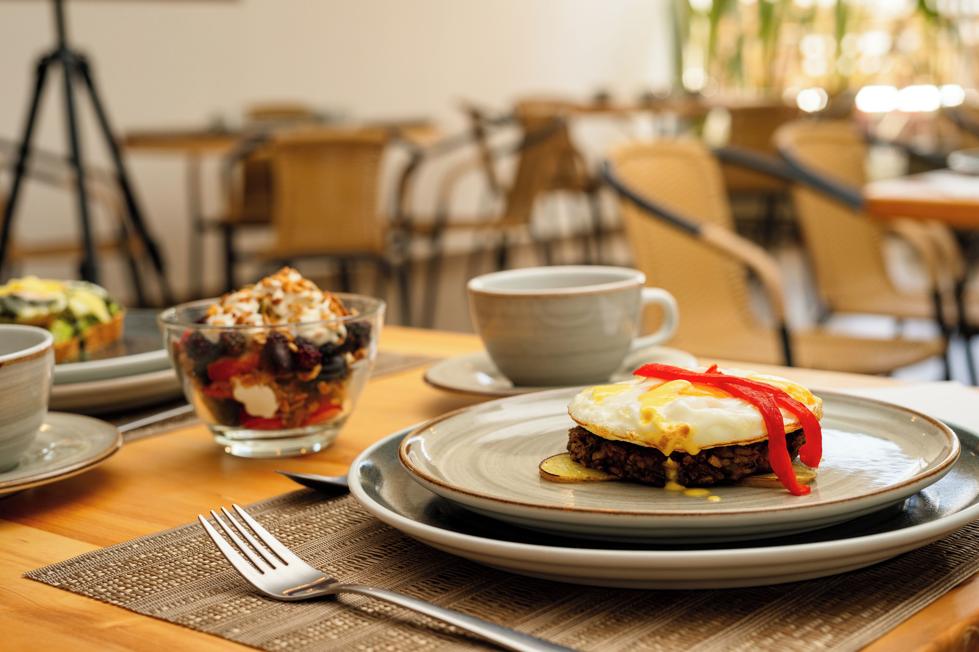 Una mesa con platos, un tazón de ensalada y una taza.