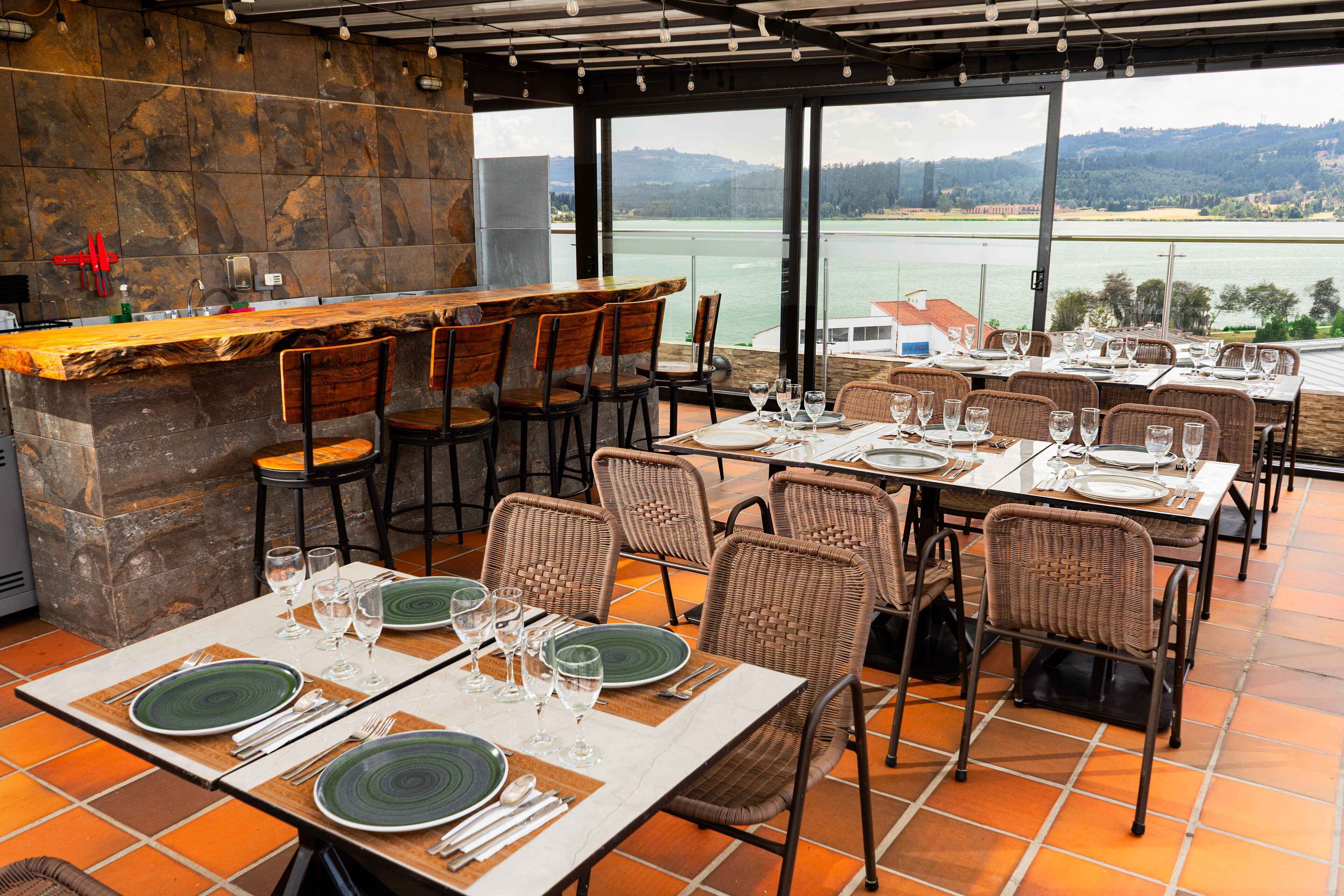 A restaurant with outdoor seating overlooking a body of water, featuring stone walls and a bar area.