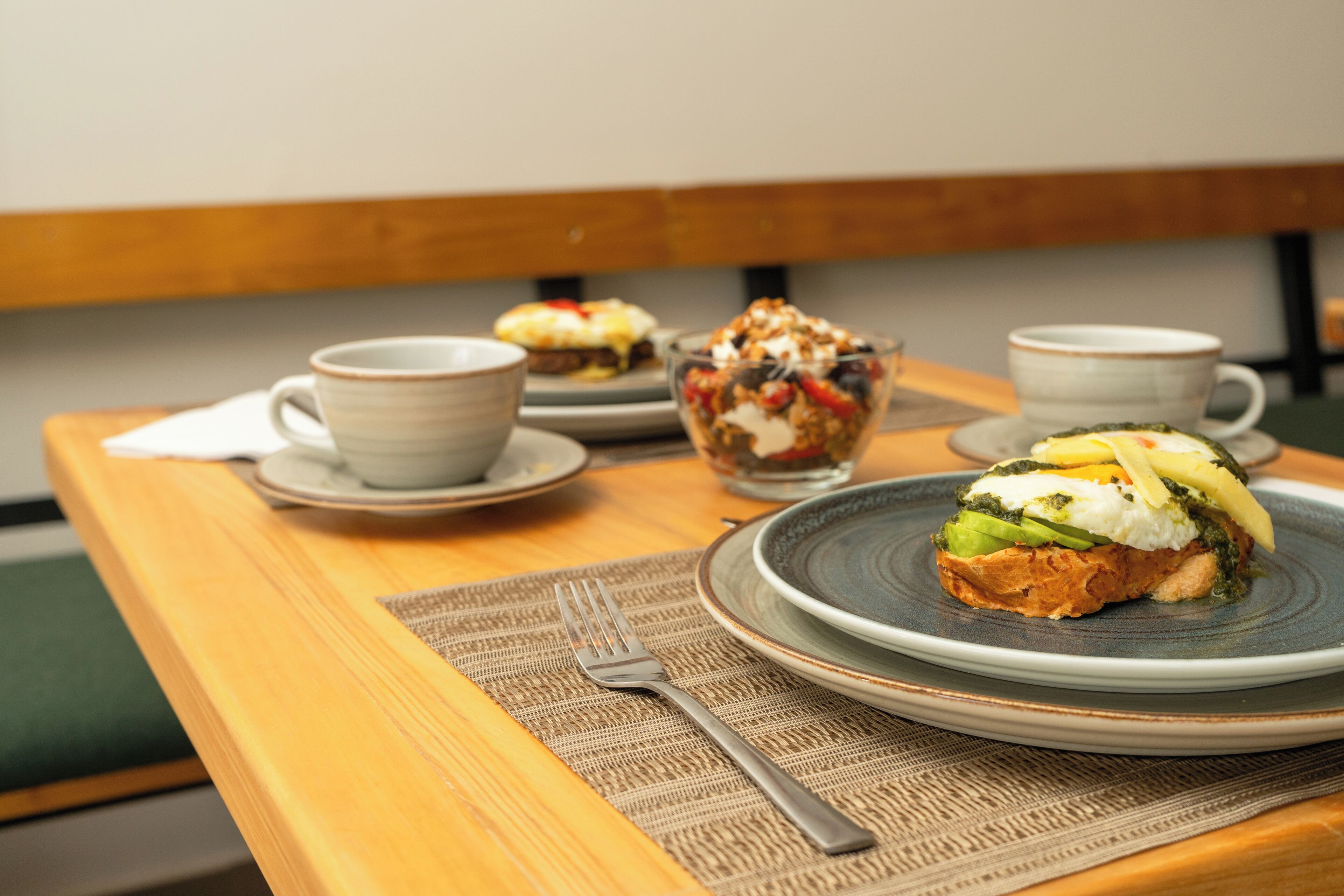 A wooden table with a plate of food, a cup, and a fork.
