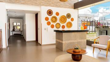 Un intérieur moderne avec un îlot central, un coin salon et un mur orné de motifs circulaires.