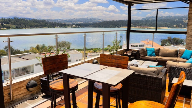Une terrasse avec vue sur un lac, aménagée avec une table, des chaises et un canapé.