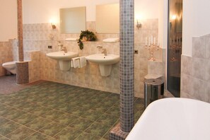 Une salle de bain avec deux lavabos, des toilettes et une baignoire.