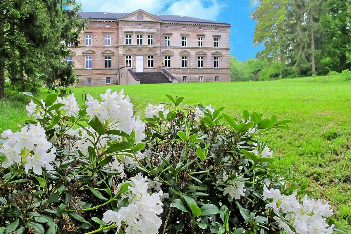Een groot, historisch gebouw met een symmetrische gevel, veel ramen en een centrale ingang.