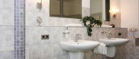 Une salle de bain moderne avec deux lavabos, un grand miroir et une colonne décorative.
