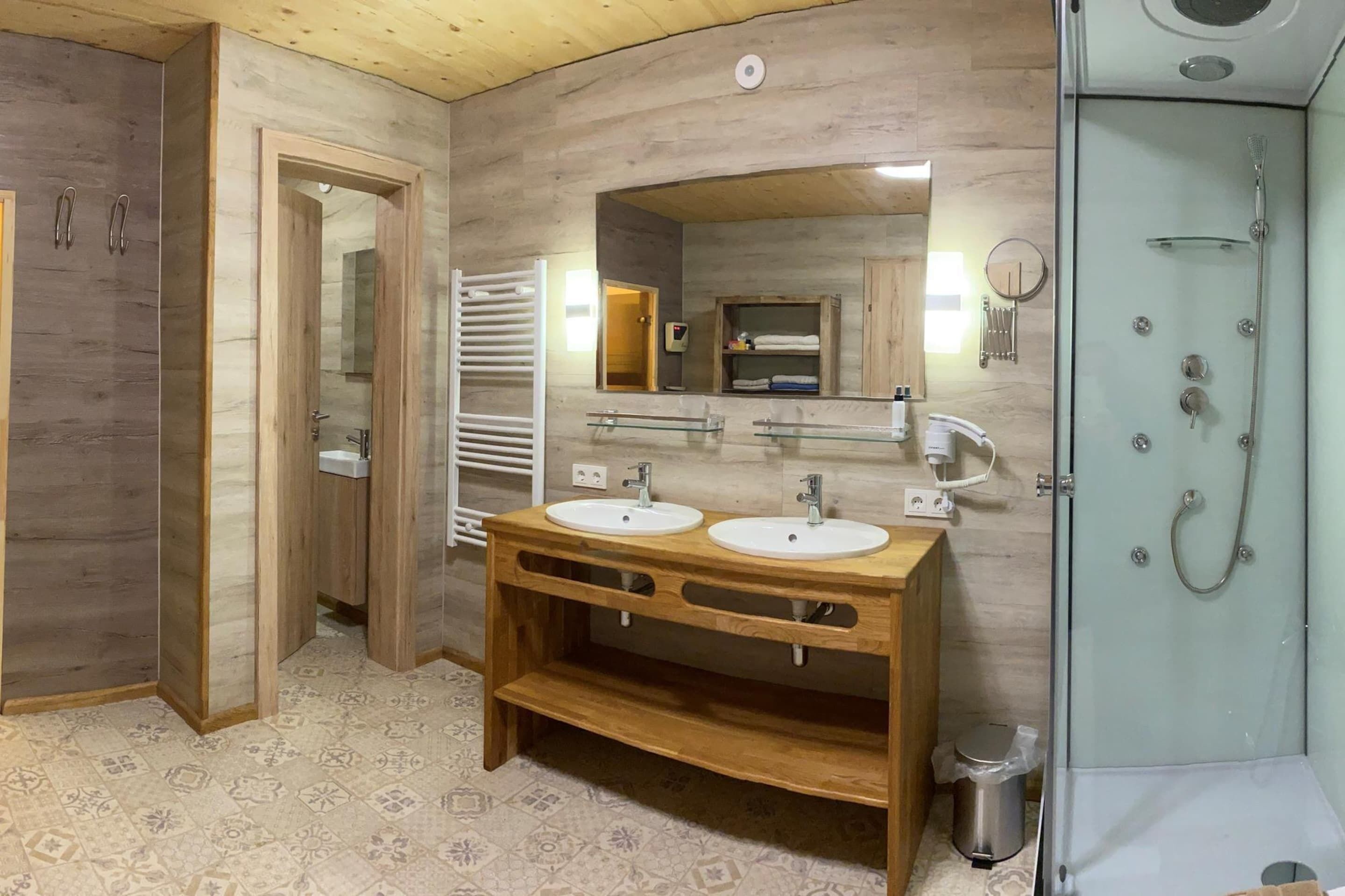 A bathroom with two sinks, a mirror, a shower, and a towel rack.