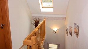 A staircase with a wooden handrail, a skylight, and wall-mounted lighting. - Doppelhaushalfte Ostseehaus I in Trassenheide (Trassenheide)