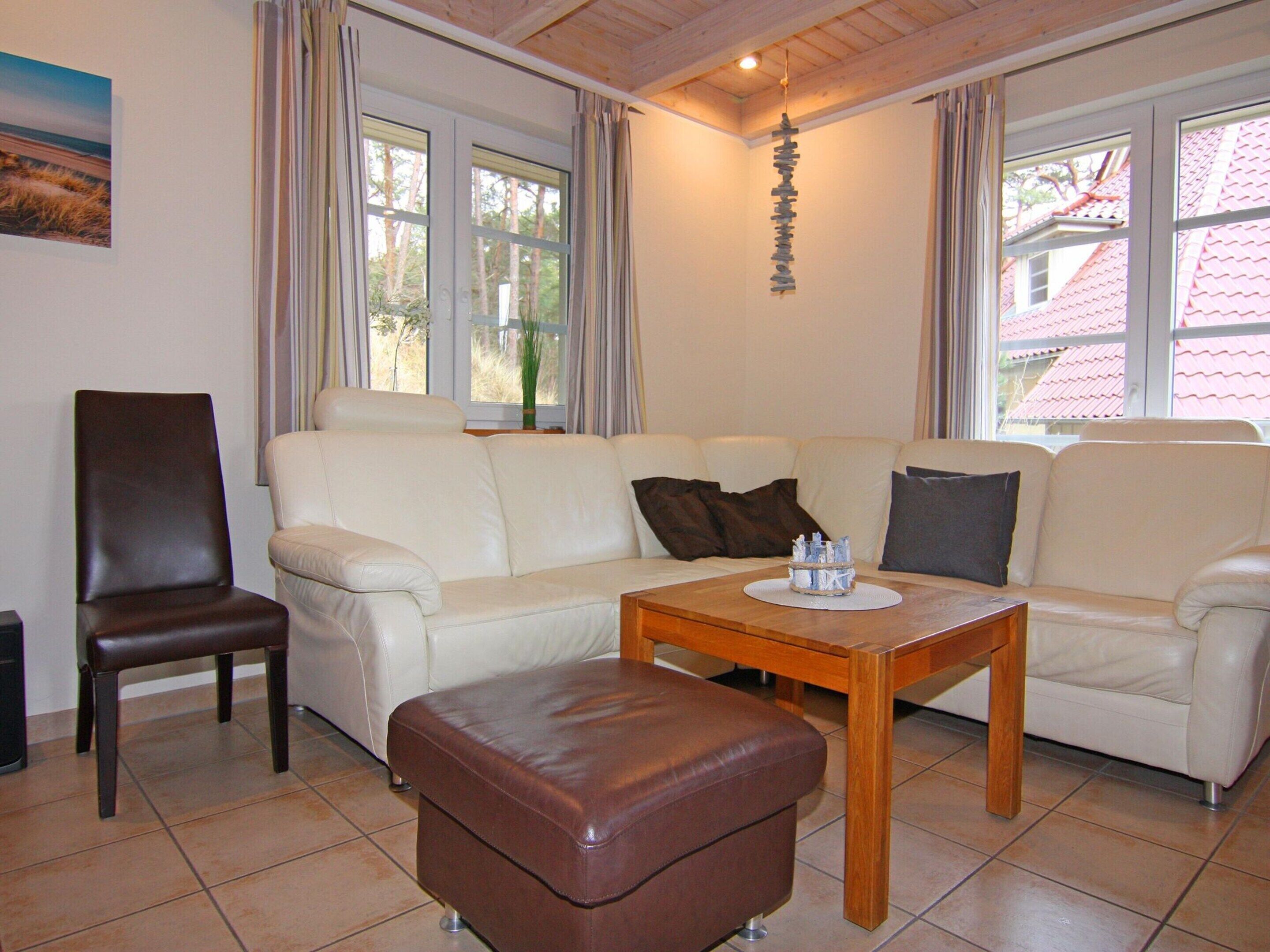 A living room with a sofa, a chair, a coffee table, and a hanging decoration.