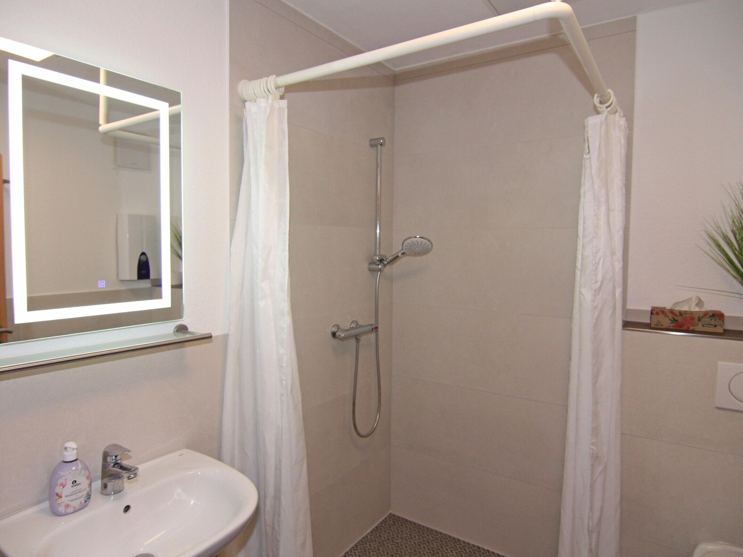 A bathroom with a shower, a sink, and a mirror.