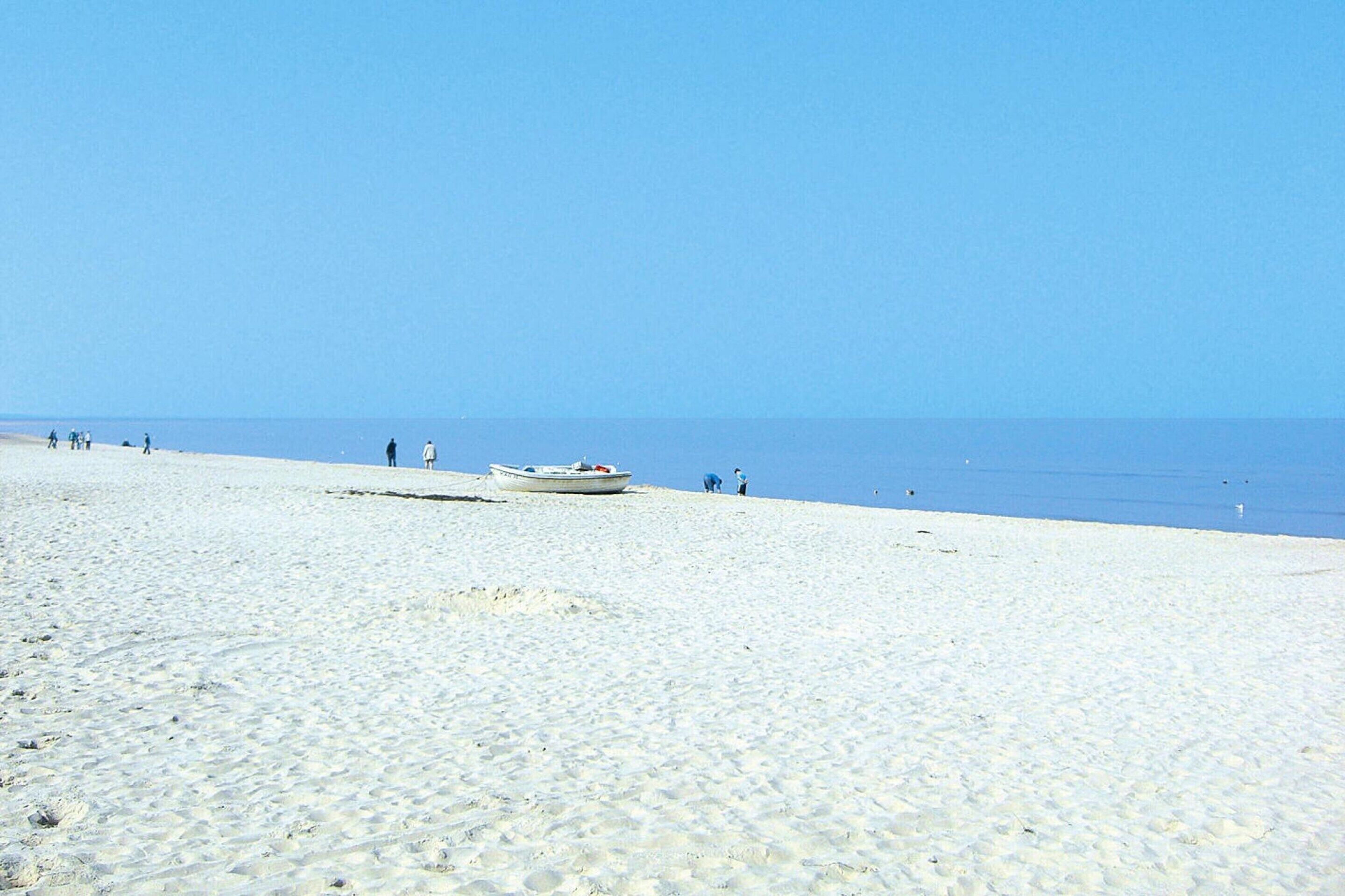 Une plage de sable avec un bateau et des personnes au loin.
