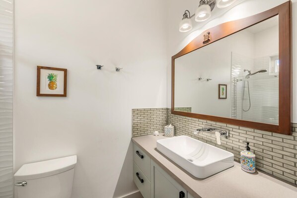Un baño moderno con un lavamanos blanco, un espejo grande y un inodoro.