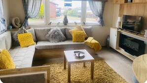 A cozy living room with a sofa, a coffee table, and a TV. - Cosy Hottub Caravan Retreat in Lincolnshire (Lincoln)