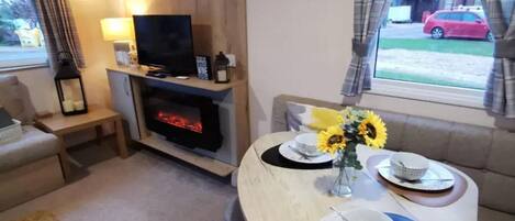 A cozy living area with a fireplace, a dining table set for four, and a sofa.
