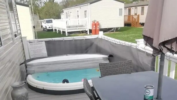 A backyard with a hot tub, a table, and a covered area. - Cosy Hottub Caravan Retreat in Lincolnshire (Lincoln)