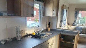 A compact kitchen with a sink, cabinets, and a window. - Cosy Hottub Caravan Retreat in Lincolnshire (Lincoln)