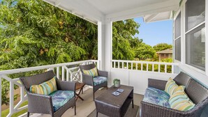 A covered porch with wicker furniture and a view of lush greenery. - koolkondo 2606 Halalu Guest house (Koloa)