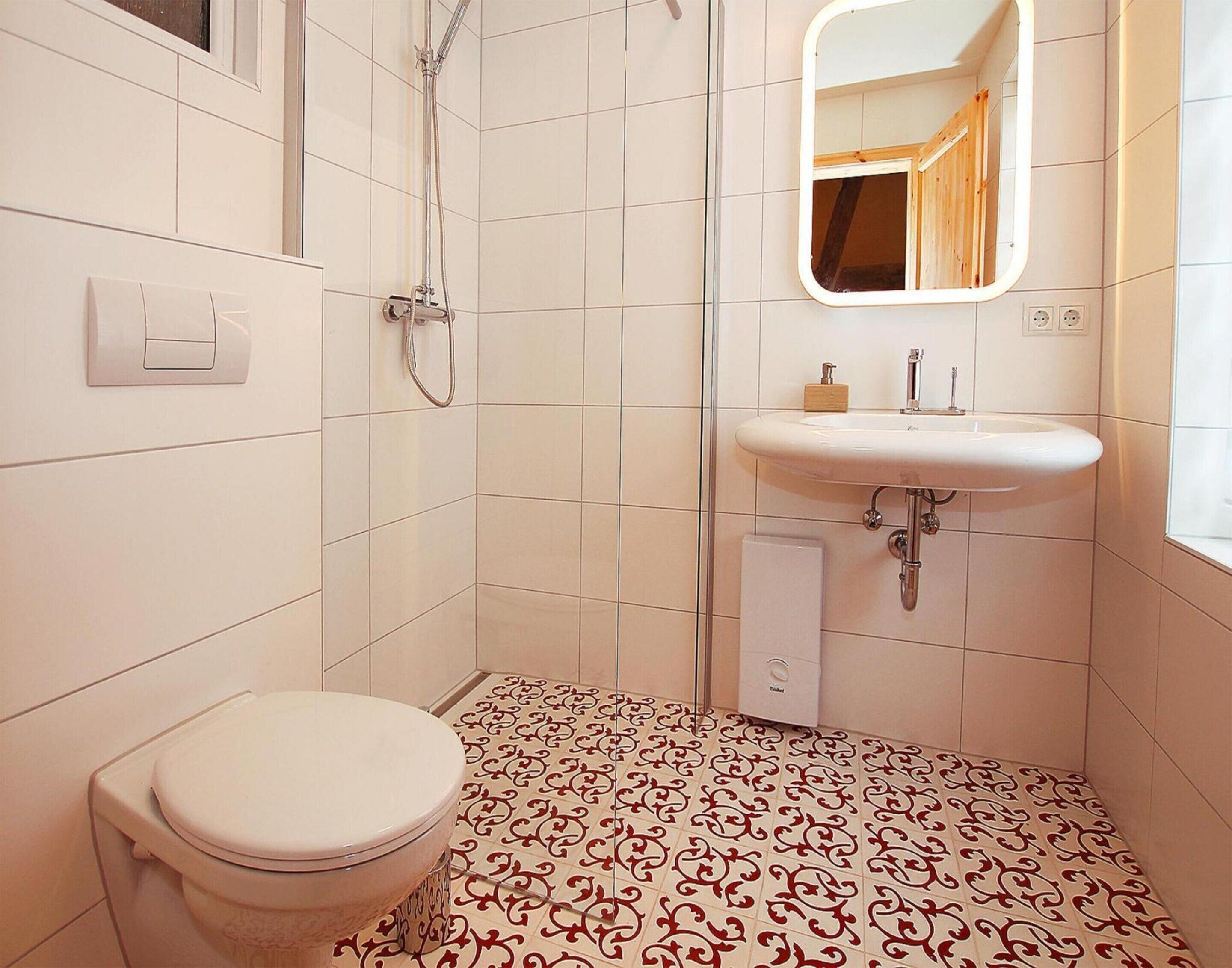 A bathroom with a toilet, a shower, and a sink.