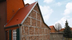 Et traditionelt murstenshus med et stejlt tag og en lille veranda.