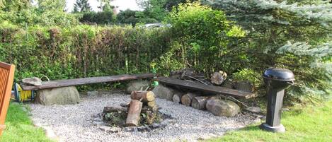 A garden with a fire pit, wooden benches, and a metal lantern.