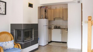 A compact kitchen with a built-in fireplace, a refrigerator, and wooden cabinets. - Detached Cottage With Fenced Yard Right by the Lake, Wrony (Gizycko)