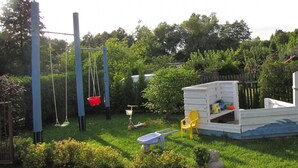 A fenced garden with a play area, including swings and a small playhouse. - Detached Cottage With Fenced Yard Right by the Lake, Wrony (Gizycko)