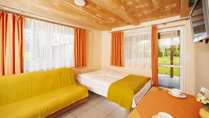 Une pièce avec un canapé jaune, un lit avec un matelas blanc et une table sur laquelle se trouvent une tasse et une soucoupe.