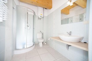 A modern bathroom with a glass shower enclosure, a white toilet, a white sink with a wooden countertop, and a mirror above the sink. - Cottage With a Terrace for 2 People, Kolobrzeg (Kolobrzeg)