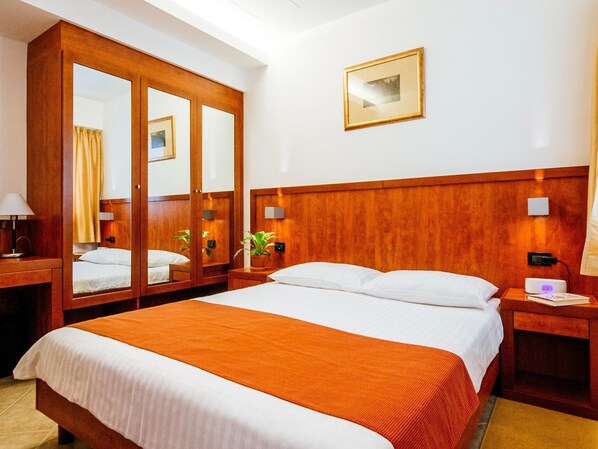 A hotel room with a large bed, wooden wardrobe, bedside tables, a mirror, and a framed picture on the wall. - Family Fun at Zaton Resort (Nin)