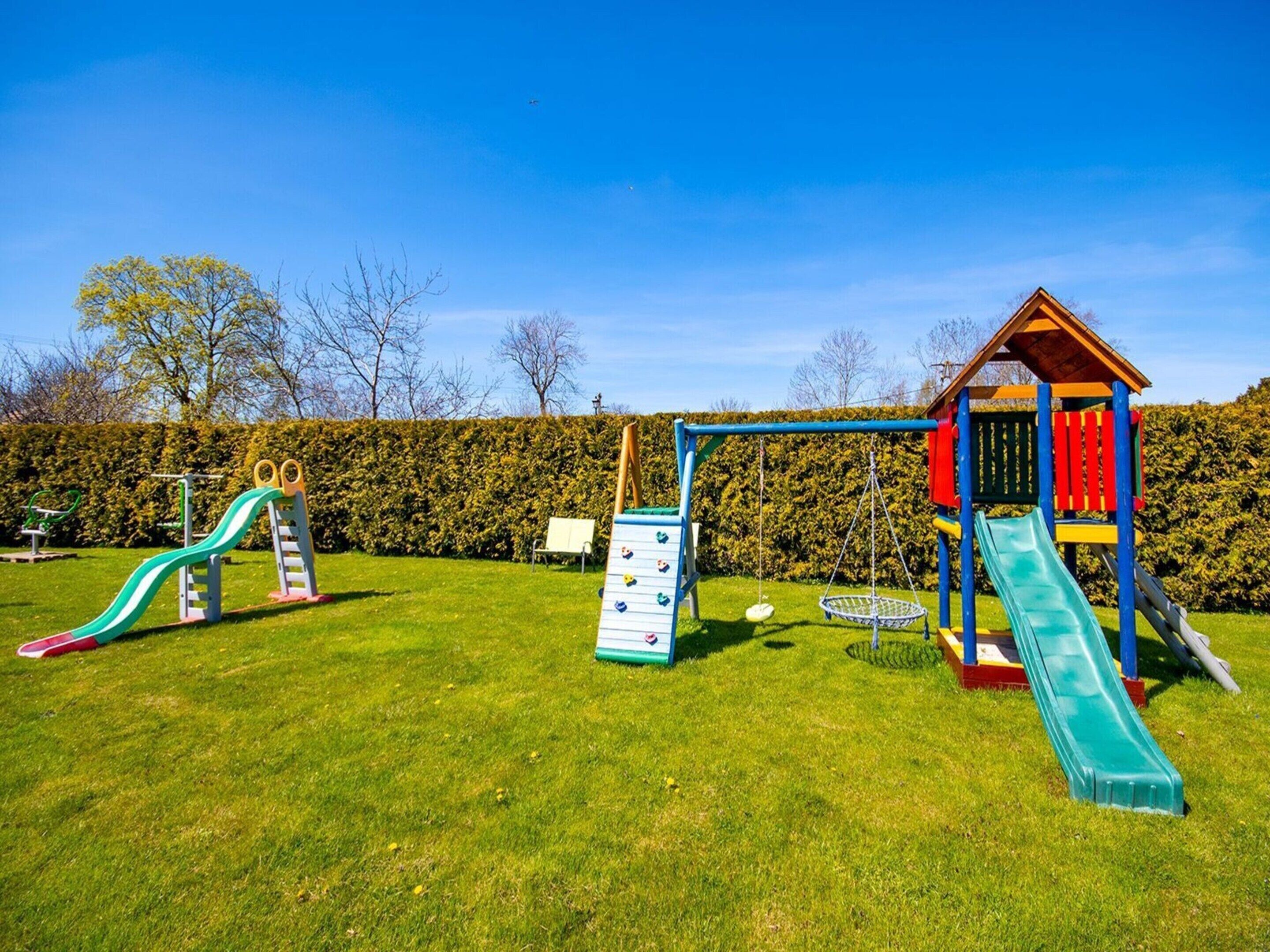 A playground with slides and climbing structures in a grassy area.